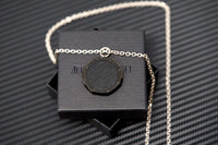 Stylish black Royal Oak medallion pendant positioned against matte background